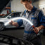 Mechanic inspecting a car with a flexible inspection light in a garage.