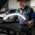 Mechanic inspecting a car with a flexible inspection light in a garage.