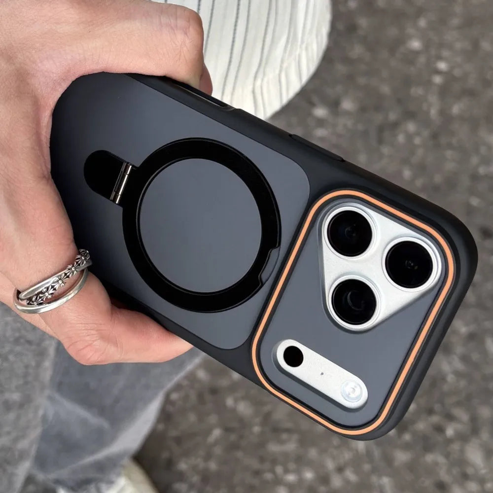 Hand holding a black phone case with a ring holder on a blurred background