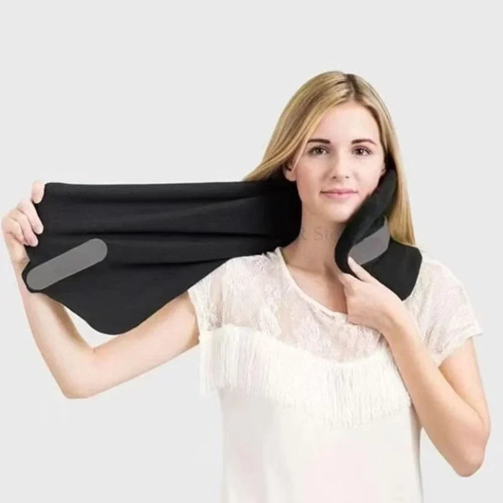 A woman wearing a white lace top holds up a black neck support pillow with gray padding against a light gray background.