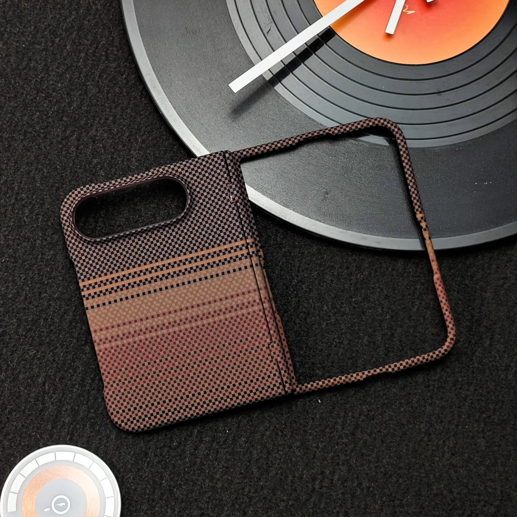 A smartphone case with a textured black and brown gradient pattern, displayed on a dark textured surface next to a vinyl record prop.