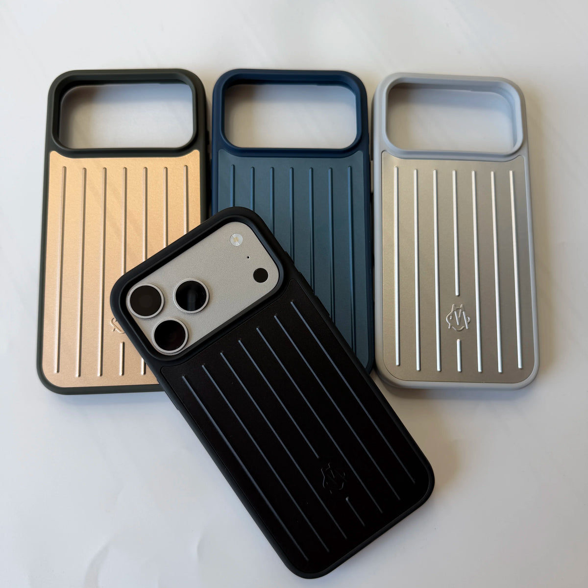 Three slim protective phone cases with a vertical stripe design are displayed on a white surface, with one black case in the foreground holding a smartphone.