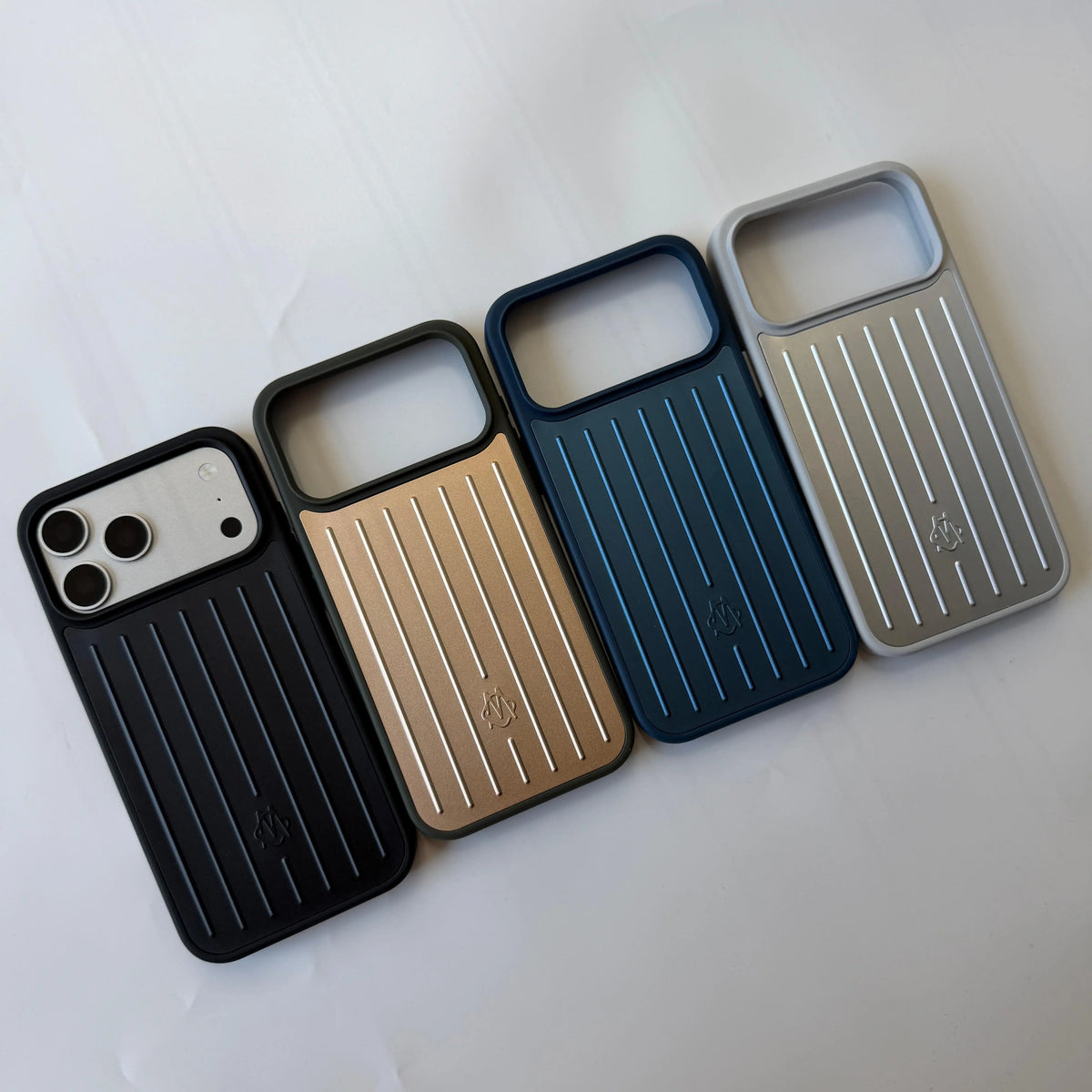 Four protective phone cases with a vertical ribbed design are arranged diagonally on a white background. The cases are shown in black, gold, dark blue, and light gray/silver.