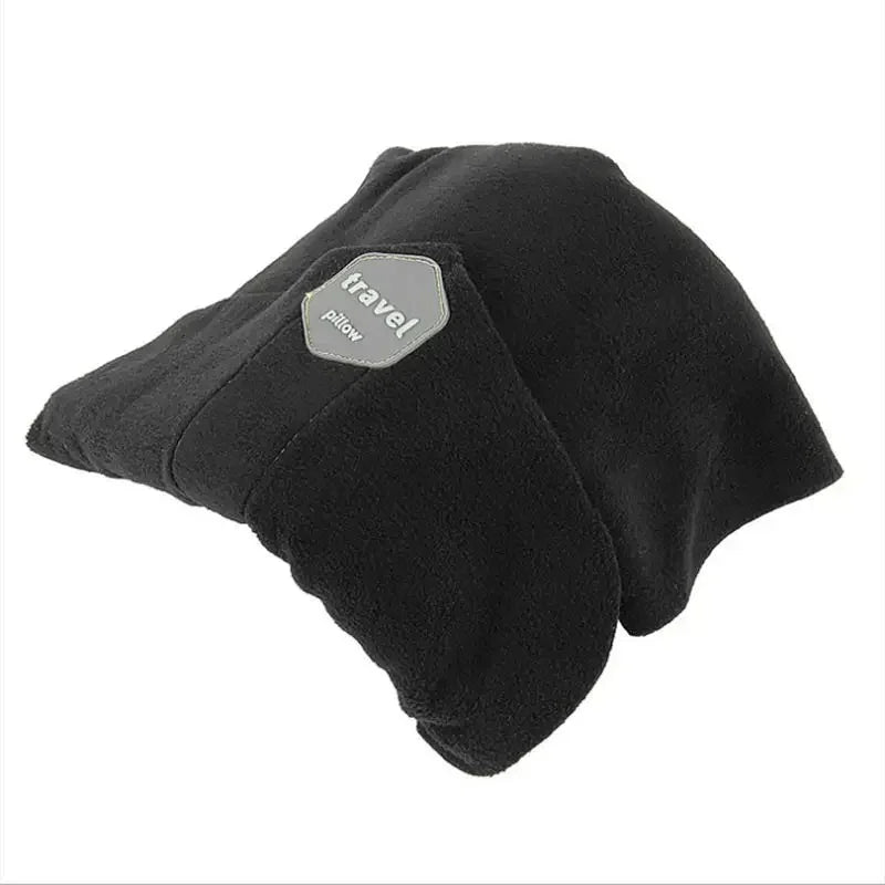A black fleece travel pillow with a gray hexagonal patch that reads 'travel pillow', shown on a plain white background.