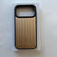 A protective phone case with a metallic gold backplate featuring vertical grooves and a black bumper frame, resting on its white retail box.
