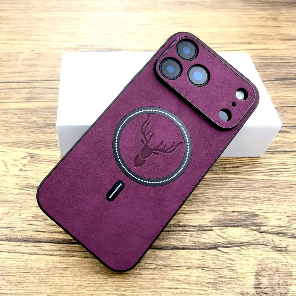 A dark purple phone case with a black magnetic ring and deer logo, shown on a smartphone resting on a white box over a wooden surface.