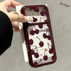 A hand holds a phone case with a glossy dark red bumper and a clear back decorated with an all-over 3D cherry print. The case is shown on a phone, with a white card backing visible behind it.
