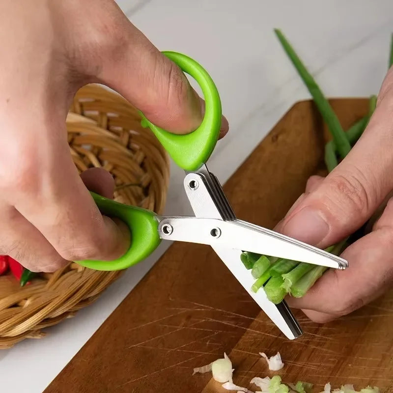 Person using green-handled scissors to trim green onions on a wooden cutting board.