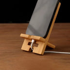 adjustable wooden phone stand holding smartphone upright with charging cable plugged into base