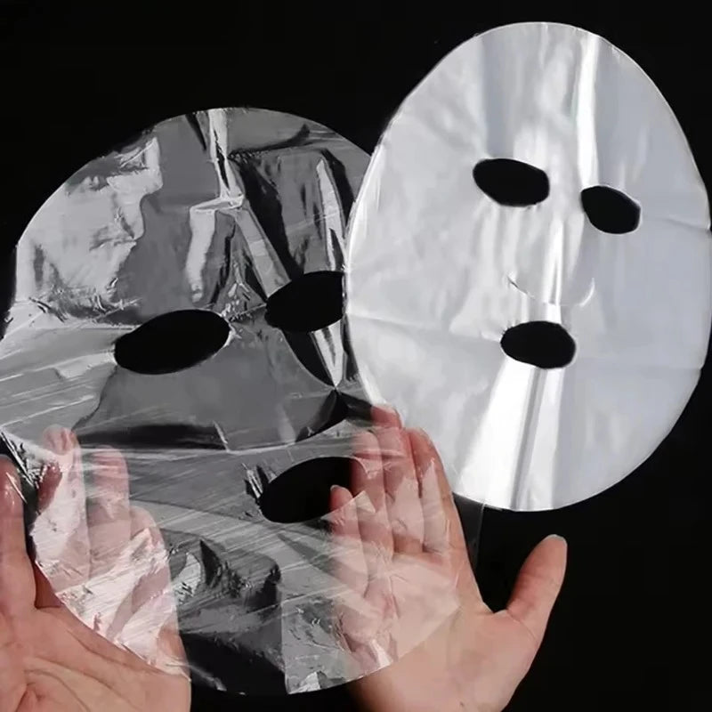 disposable plastic face mask wrap sheet held in hand for deep serum absorption and facial skincare spa wrap Main image