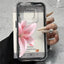 Phone case with pink flower design held by a hand on a gray surface