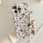 A hand holding a white phone case decorated with a delicate red and black floral pattern, featuring a pearl-bead wrist strap.