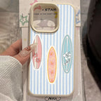 A hand holds a phone case on its retail packaging. The case has a light blue and white vertical stripe pattern with three colorful surfboard graphics (pink, orange, and light blue) decorated with floral designs.