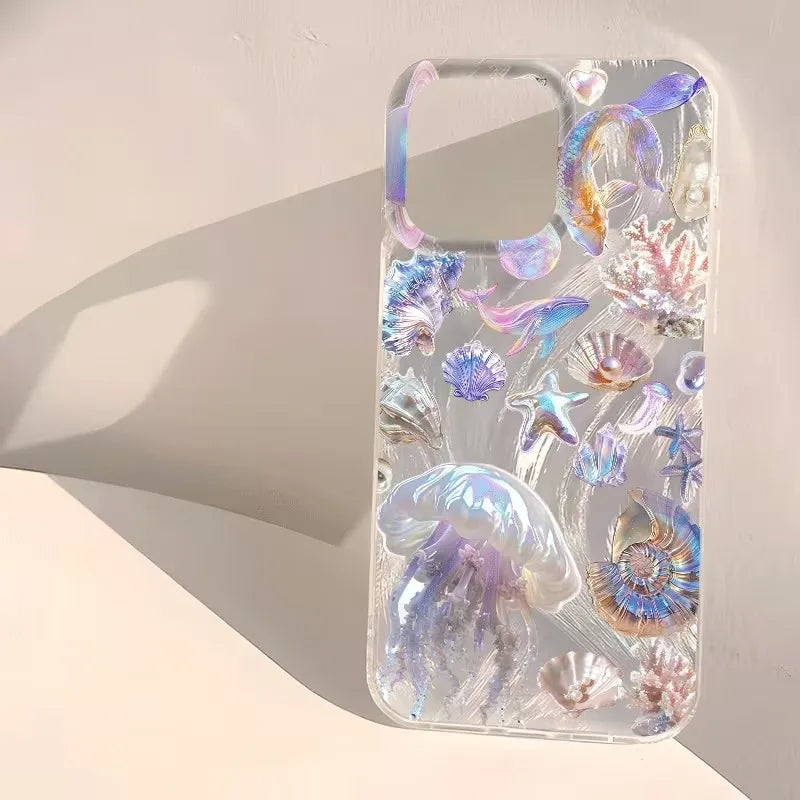 A clear phone case decorated with holographic, iridescent sea life motifs including jellyfish, starfish, and seashells, displayed on a warm beige surface with a soft shadow.