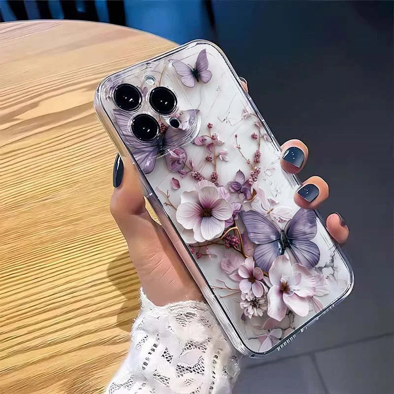 Phone case with floral and butterfly design held by a hand on a wooden surface.