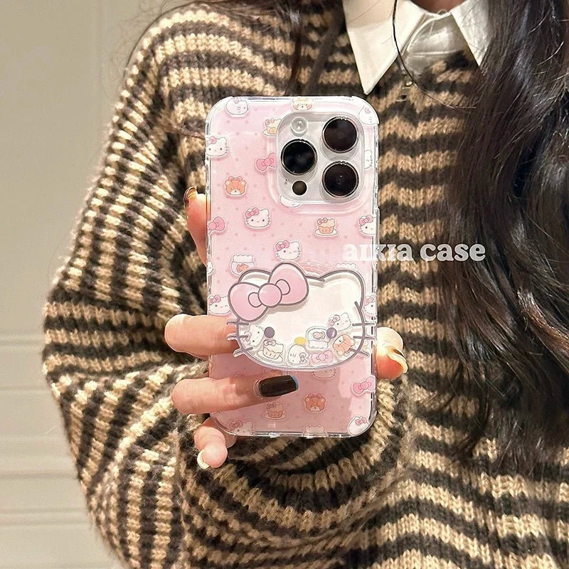 A person holding a pink Hello Kitty phone case with a clear bumper, wearing a brown and beige striped knit sweater.