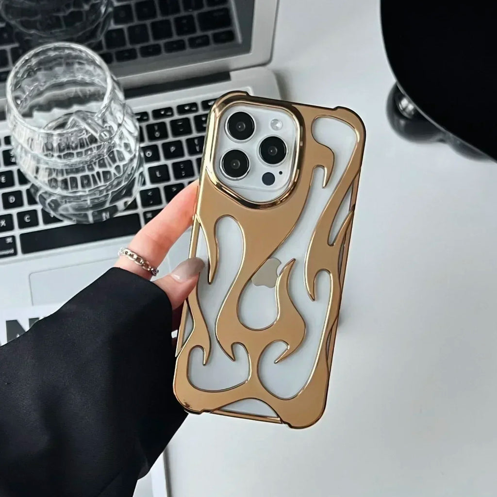 Gold flame-patterned phone case held by a hand on a desk with a laptop and glass.