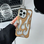 Gold flame-patterned phone case held by a hand on a desk with a laptop and glass.