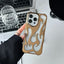 Gold flame-patterned phone case held by a hand on a desk with a laptop and glass.