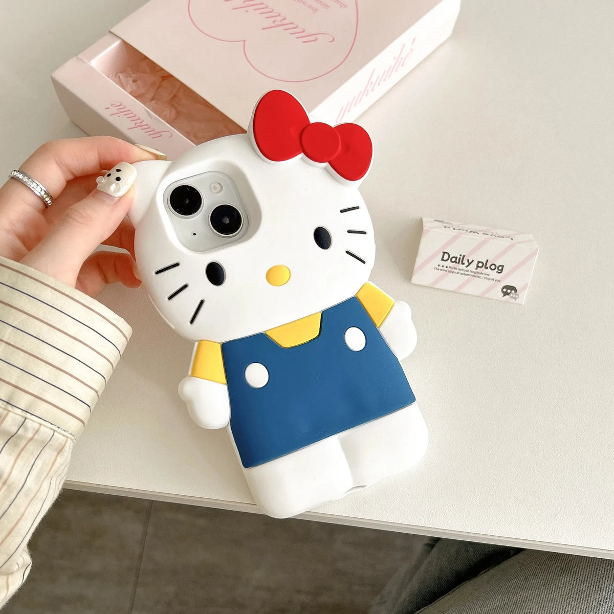 Hello Kitty phone case held by a hand on a light surface with a blurred background