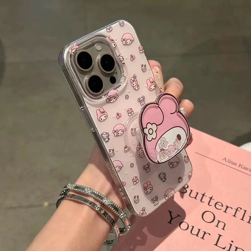 A hand holding a clear phone case with a pink cartoon bunny pattern and a matching pink stand-on grip. The phone is partially visible inside the case, and the hand is wearing two silver bracelets.