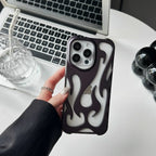 Person holding a phone with a flame design case in front of a laptop on a desk.