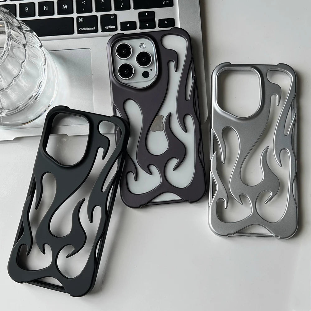 Three flame-patterned phone cases on a desk with a laptop and glass.