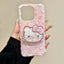 A hand holding a clear phone case decorated with a pink Hello Kitty pattern and a large 3D Hello Kitty face on the back, set against a plain beige background.