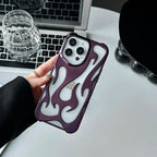 Person holding a phone with a flame design case on a desk with a laptop and glassware.