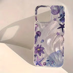A clear phone case with a purple and blue underwater theme print, featuring jellyfish, starfish, seashells, and sea plants, displayed on a warm off-white surface with a soft shadow.