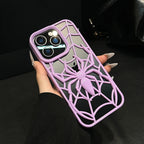 Hand holding a phone with a purple spider web design case against a dark background