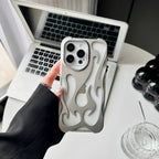 Person holding a phone with a unique case in front of an open laptop on a desk.
