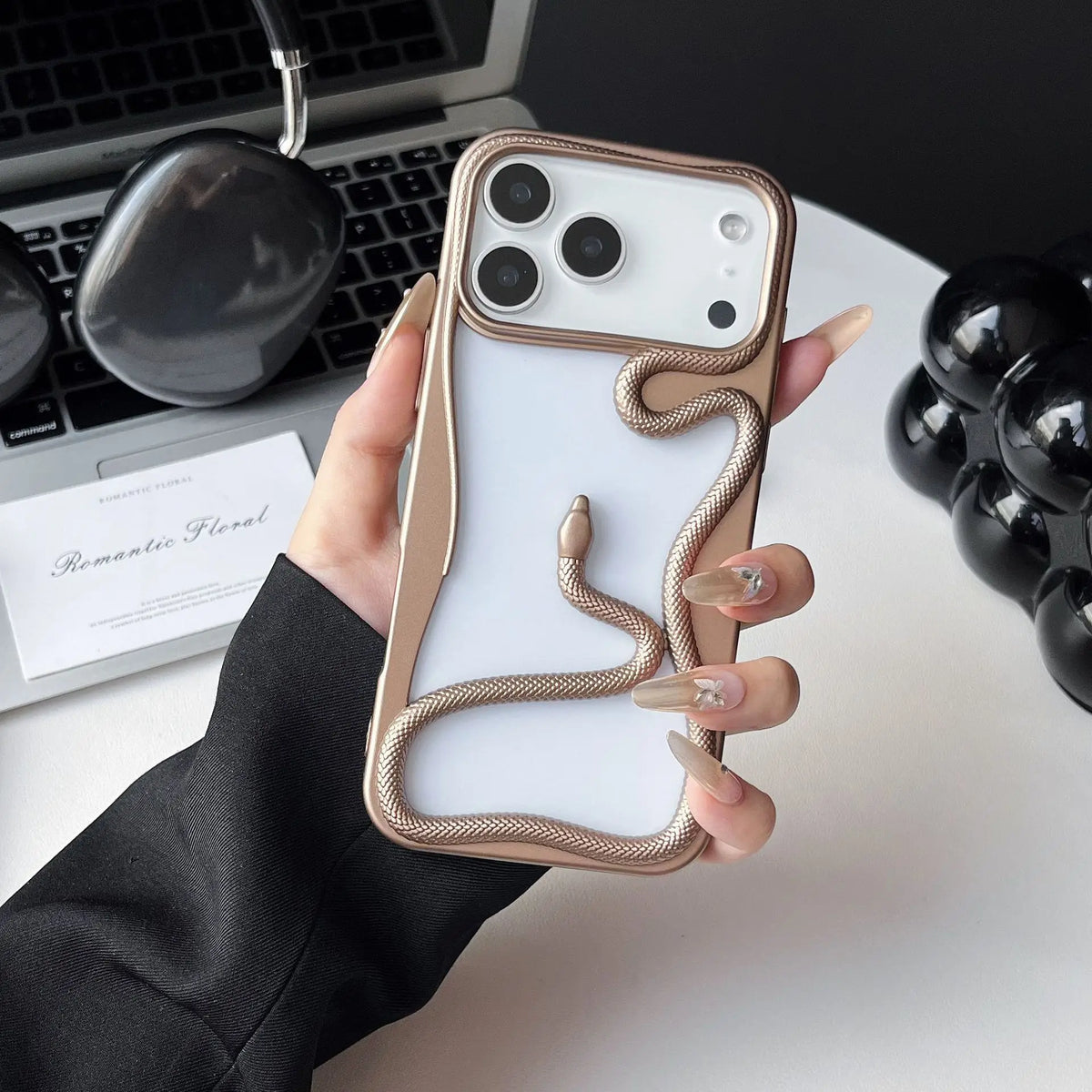 Phone case with snake design held by a hand on a desk