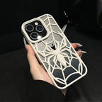 Phone case with spider web design held by a hand against a dark background