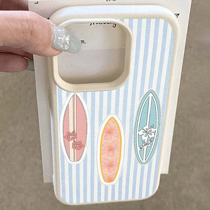 A hand with glittery fingernails holds a phone case featuring a light blue and white vertical stripe pattern with three surfboard designs in pink, orange, and blue.