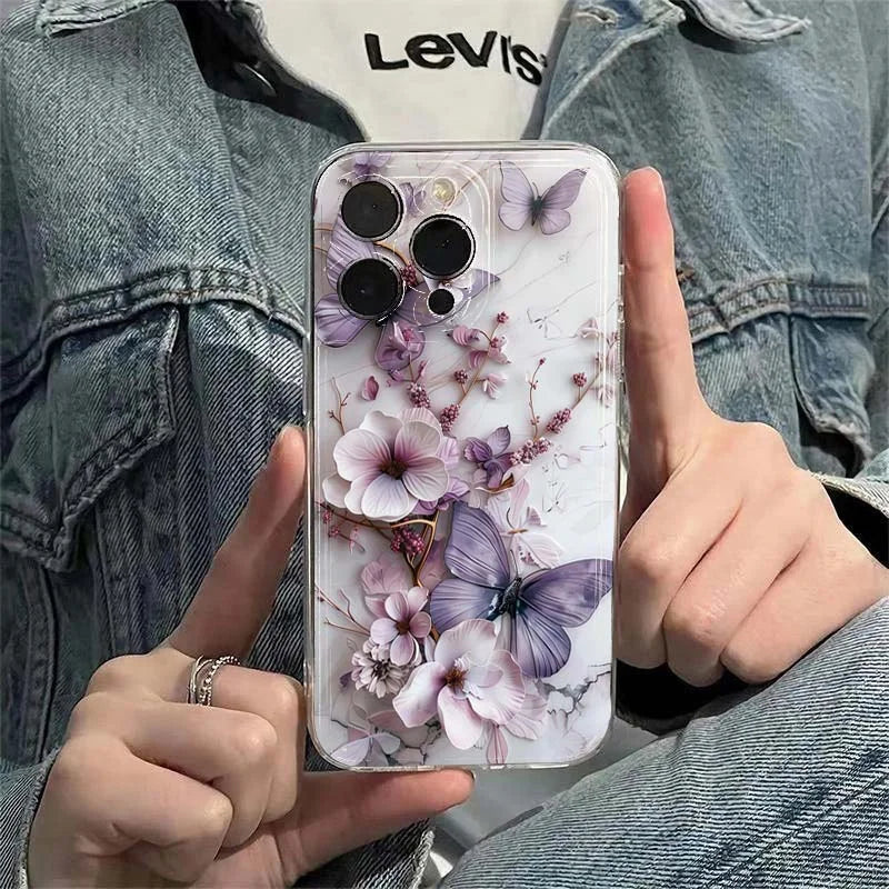Person holding a phone with a floral and butterfly design case, wearing a denim jacket.