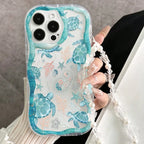 Phone case with turtle design held by a person wearing a pearl bracelet.