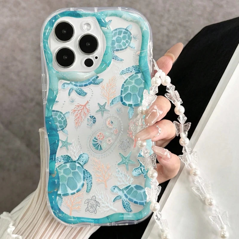 Phone case with turtle design held by a person wearing a pearl bracelet.