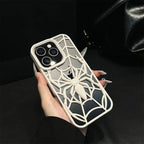 Phone case with spider web design held by a hand against a dark background