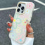 Phone case with colorful floral design held by a hand against a dark background