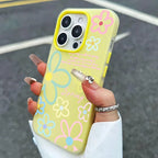 Hand holding a phone with a yellow case featuring colorful floral designs on a dark surface.