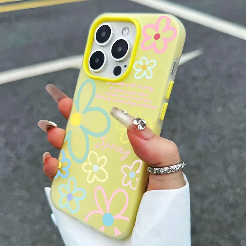 Hand holding a phone with a yellow case featuring colorful floral designs on a dark surface.