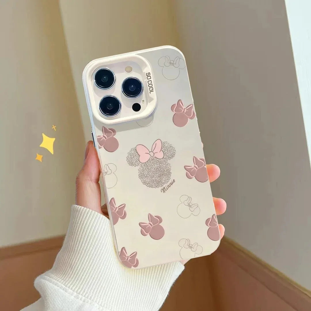A hand holding a phone case decorated with pink bow and Minnie Mouse-inspired bow motifs on a cream background, shown against an indoor wall corner.