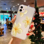 Hand holding a phone case with yellow floral design in a blurred indoor setting