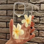 Clear phone case with yellow flowers held against a brick wall.