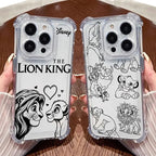 Two clear phone cases with black printed Disney The Lion King artwork are held by hands over a brown wooden surface. One case shows a large lion face and the title 'THE LION KING,' and the other shows multiple lion characters in line art.