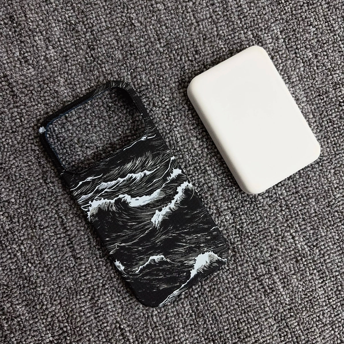Phone case with wave design and white square object on gray surface