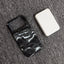 Phone case with wave design and white square object on gray surface