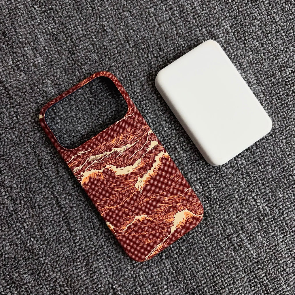 A phone case with a textured red and orange wave pattern, shown next to a plain white rectangular item on a dark gray textured fabric background.