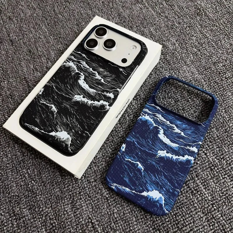 Two phone cases with an ocean wave print are displayed on a gray textured carpet. One case is shown attached to a white smartphone in its original box, while the second case is shown loose next to it.